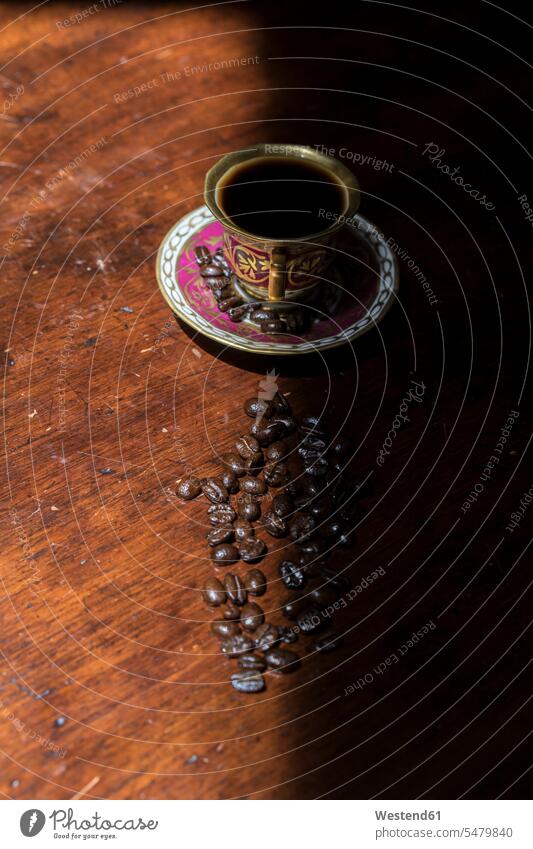 https://www.photocase.com/photos/5479840-cup-of-coffee-and-raw-coffee-beans-lying-on-shaded-table-photocase-stock-photo-large.jpeg