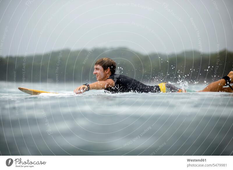 Indonesia, Java, man lying on surfboard on the sea Sea ocean surfing surf ride surf riding Surfboarding surfer surfers laying down lie lying down surfboards