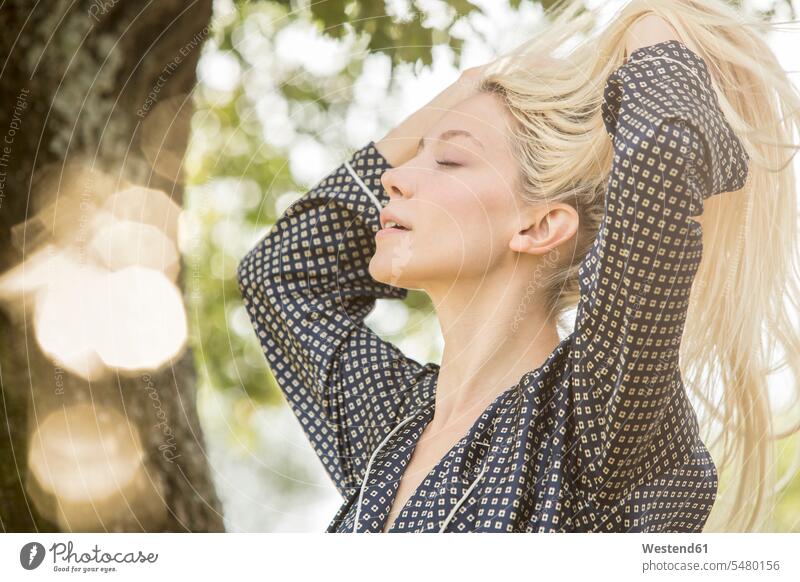 Blond woman with eyes closed and hands in her hair in the morning blond blond hair blonde hair females women people persons human being humans human beings