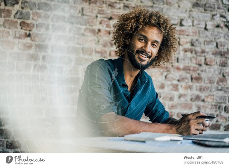 Portrait of smiling young man at desk smile desks Businessman Business man Businessmen Business men males Table Tables business people businesspeople