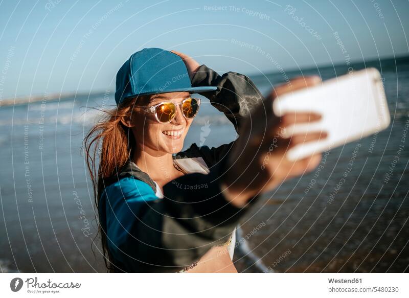 Young woman taking a selfie on the beach Selfie Selfies females women beaches smiling smile photographing Adults grown-ups grownups adult people persons