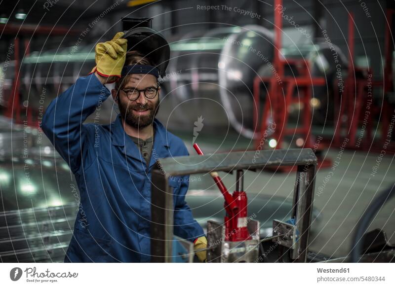 Portrait of smiling man wearing a welding mask in a factory men males Welding Masks welding helmet Welder's Visor smile worker blue collar worker workers