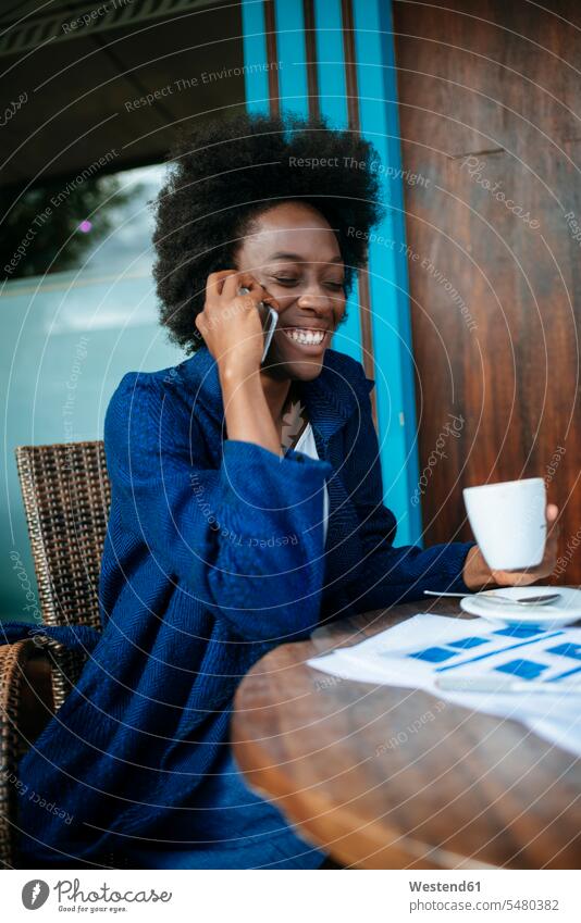 Portrait of young woman talking on mobile phone while drinking coffee in a street cafe African descent black coloured Smartphone iPhone Smartphones one person 1