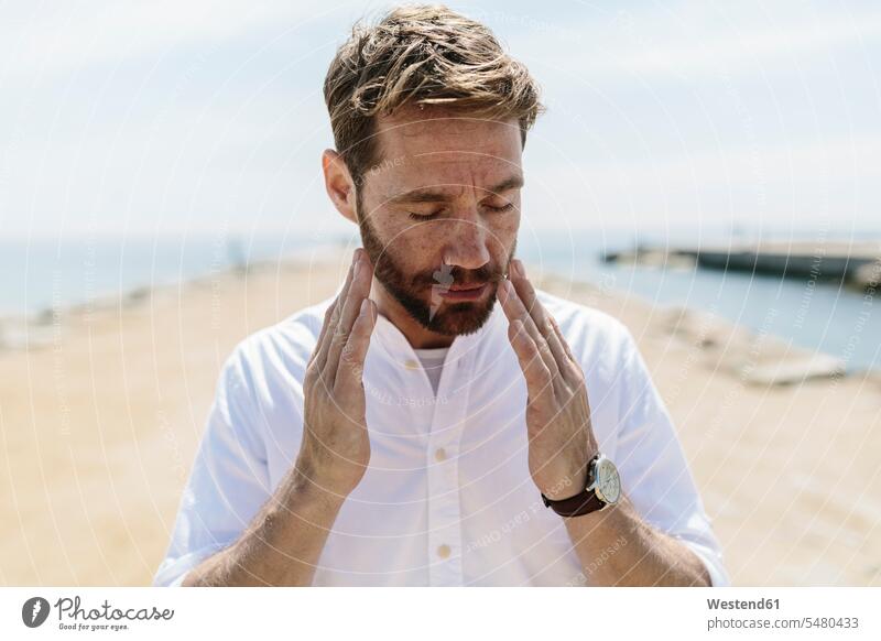 Mid adult man on the beach touching his face men males portrait portraits beaches tired Adults grown-ups grownups people persons human being humans human beings