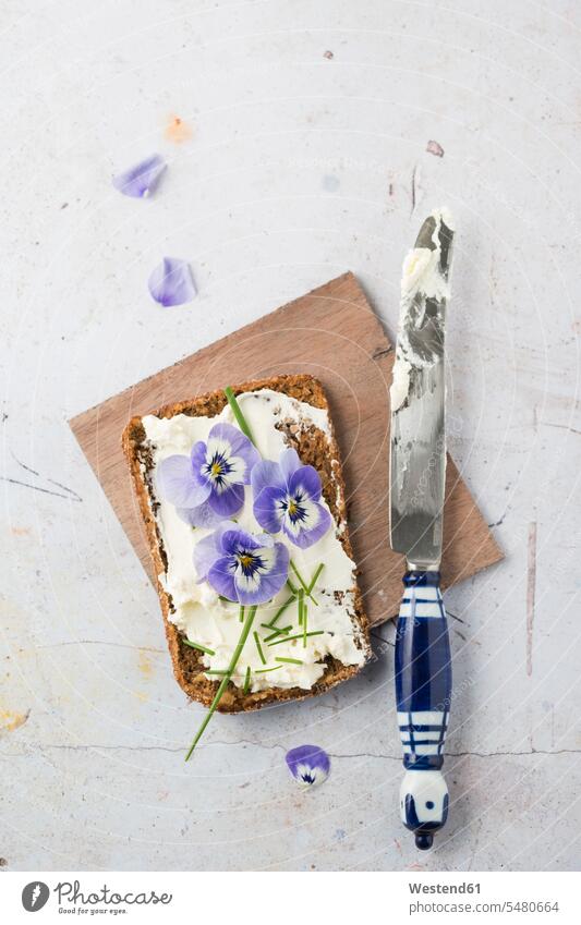 Slice of wholemeal bread with cream cheese, chives and edible Horned Violets garnished knife Table Knife Table Knives knives flower head flower heads