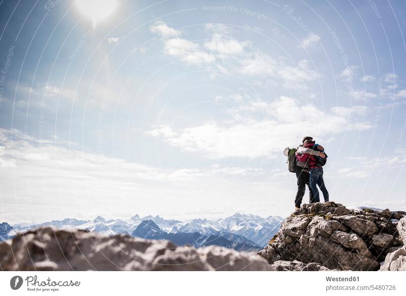 Germany, Bavaria, Oberstdorf, couple hugging on rock in alpine scenery Travel summit mountaintops summits mountain top mountain range mountains mountain ranges