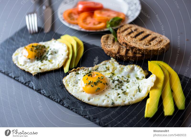 Breakfast with eggs, avovados, tomatoes and toasted bread nobody Avocado Avocados Persea americana healthy eating nutrition Slice Slices fried egg Sunny Side Up