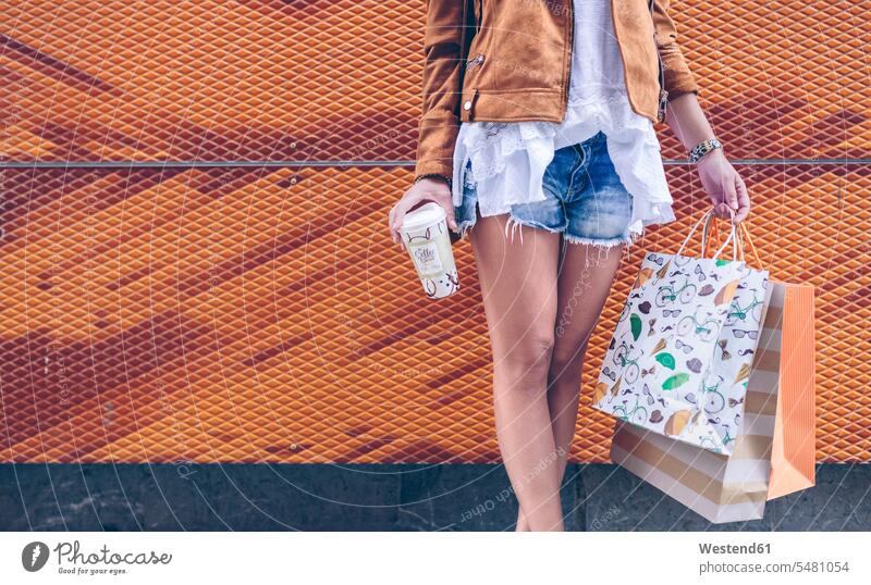 Low section of woman holding shopping bags and takeaway coffee Coffee females women shopping-bag shopping-bags Drink beverages Drinks Beverage food and drink