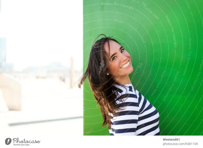 Portrait of happy woman at green wall pullover sweater jumper Sweaters leaning waist up Waist-Up upper body upper part shot casual leisure wear casual clothing