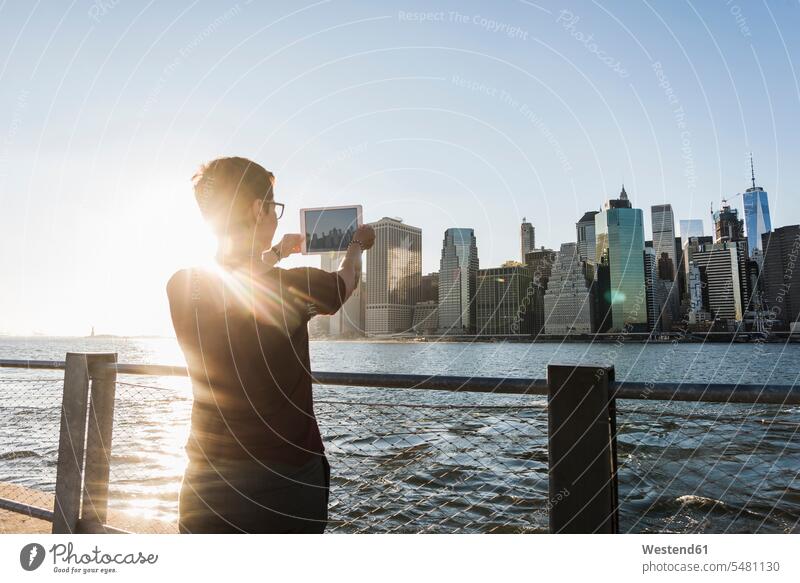 USA, Brooklyn, back view of woman taking picture of Manhattan skyline with tablet females women photographing digitizer Tablet Computer Tablet PC