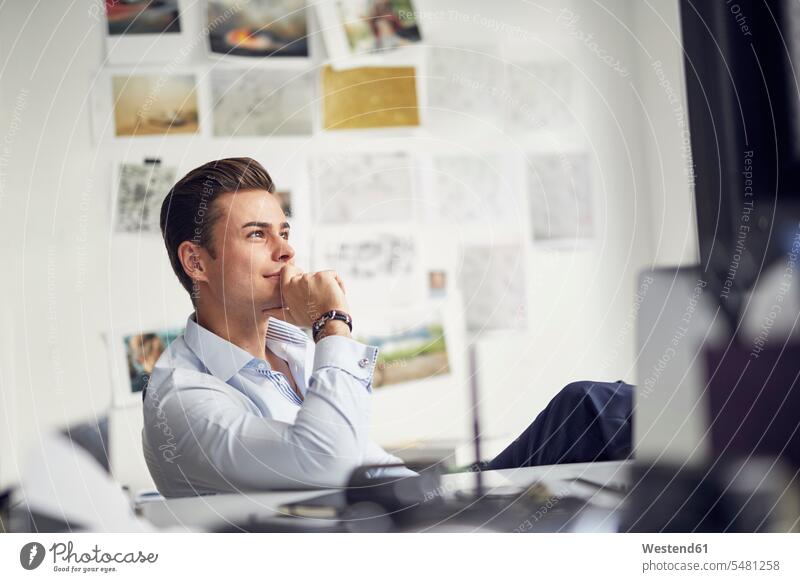 Portrait of pensive young businessman sitting at desk in the office Businessman Business man Businessmen Business men portrait portraits offices office room