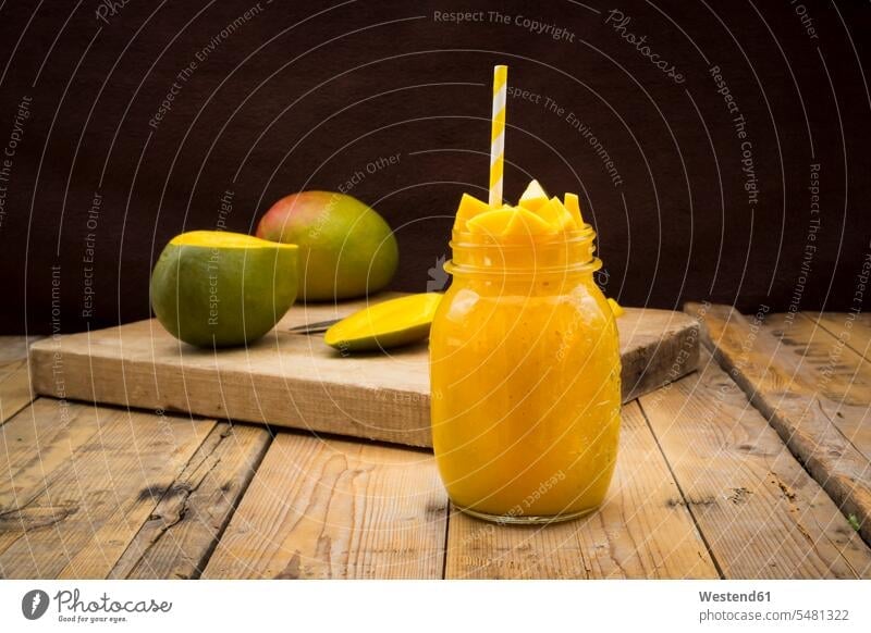Glass of mango smoothie garnished with diced mango food and drink Nutrition Alimentation Food and Drinks wooden board wooden boards wooden panel wooden panels
