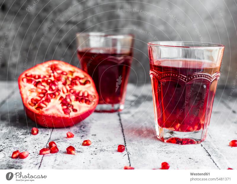 Glasses of pomegranate juice and sliced pomegranate Juice Juices nobody copy space wooden juicy half halves halved Drinking Glasses close-up close up closeups