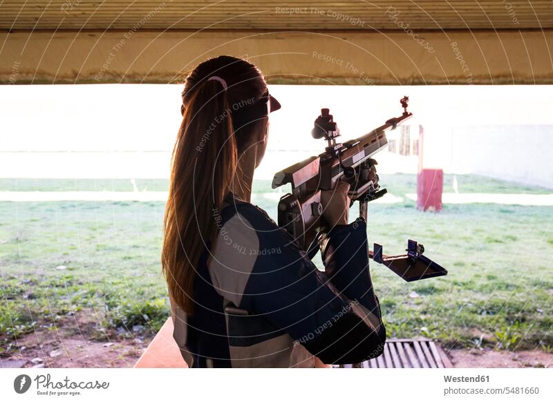 Woman in front of the targets in a shooting range gun guns rifles woman females women weapon arms weapons shooting sports Adults grown-ups grownups adult people