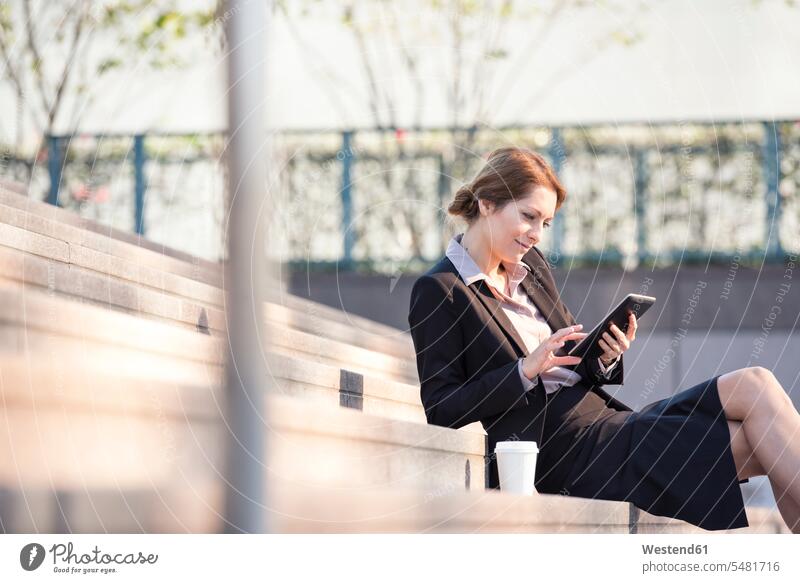 Businesswoman sitting on stairs using tablet businesswoman businesswomen business woman business women stairway digitizer Tablet Computer Tablet PC