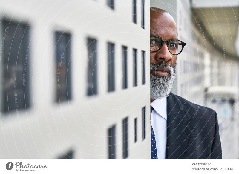 Mature businessman standing by wall, looking worried serious earnest Seriousness austere walls on the move on the way on the go on the road watching observing