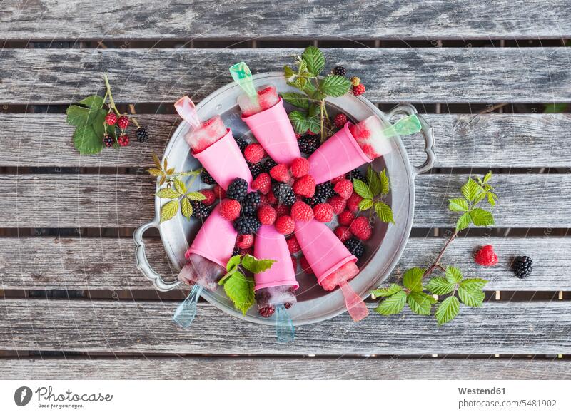 Tin plate of homemade lemonade ice lollies with raspberries and blackberries cold Cold Weather Cold Temperature chilly wooden summer summer time summery
