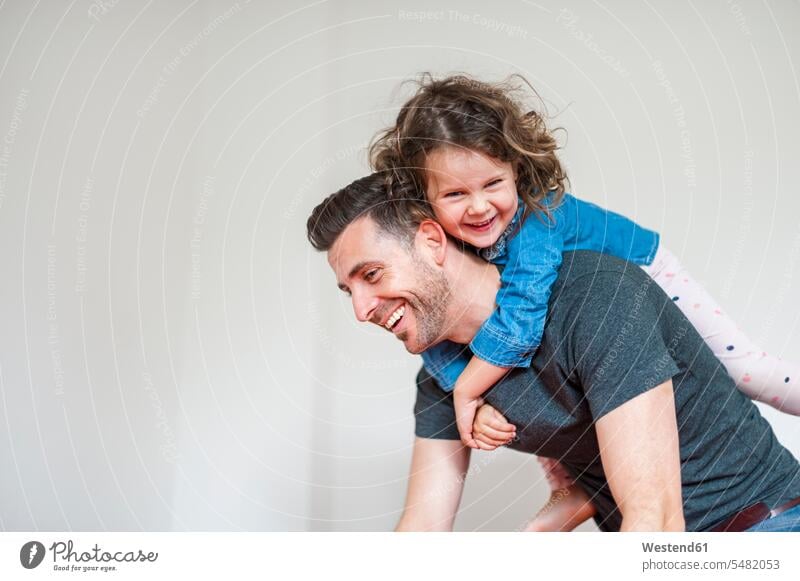 Happy father carrying daughter piggyback pa fathers daddy dads papa Fun having fun funny laughing Laughter daughters piggy-back pickaback Piggybacking