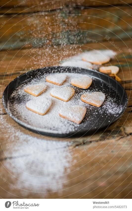 Sprinkling heart-shaped shortbreads with icing sugar on baking pan food and drink Nutrition Alimentation Food and Drinks hearts heart shapes powdered sugar