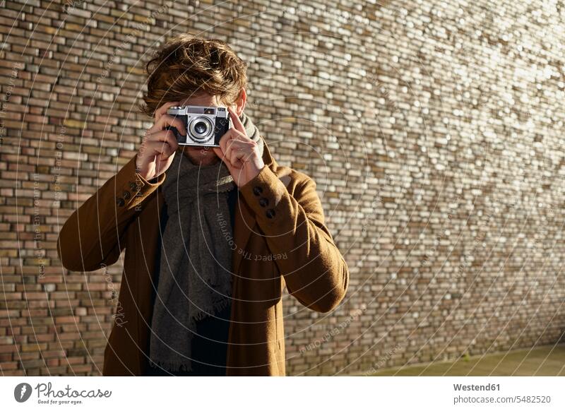 Young man taking a picture of viewer with vintage camera caucasian caucasian ethnicity caucasian appearance european Cologne waist up Waist-Up upper body