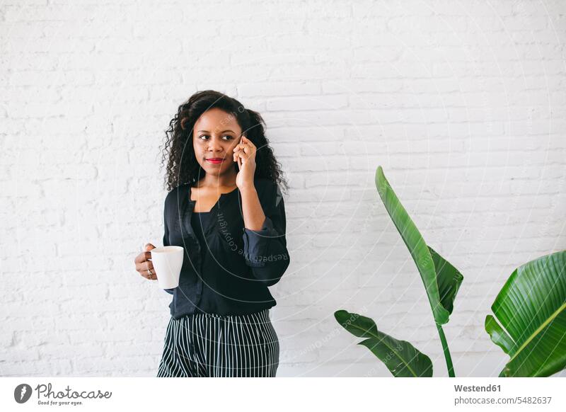 Young businesswoman standing in office, using smart phone businesswomen business woman business women females on the phone call telephoning On The Telephone