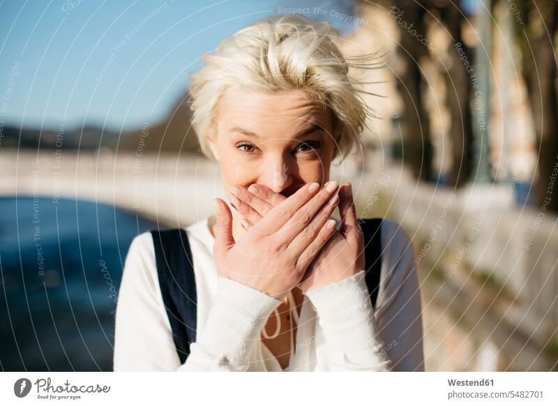 Italy, Verona, portrait of blond woman covering mouth with her hands Secret Secrets secrecy clear sky copy space cloudless caution carefully cautious beautiful