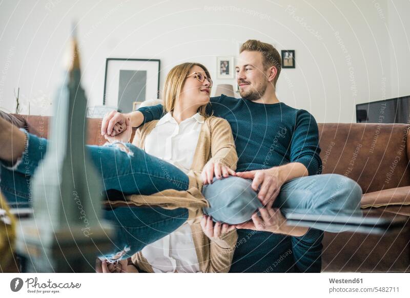 Couple sitting on couch at home with model of Empire State Building Seated models settee sofa sofas couches settees couple twosomes partnership couples people