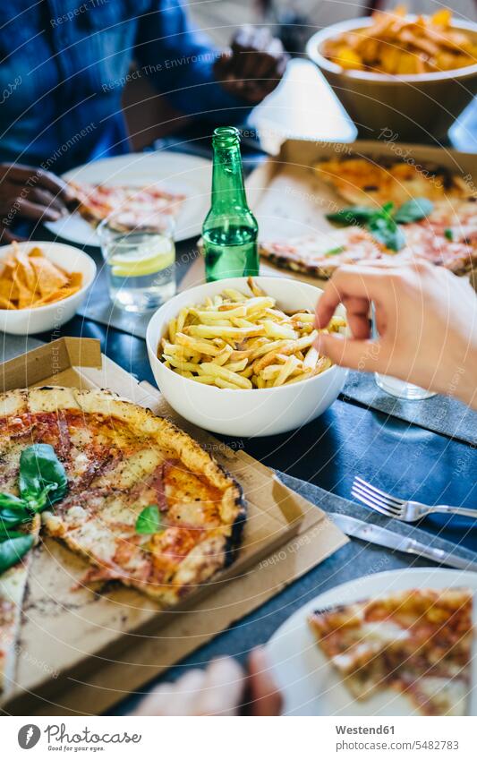 Hand reaching for French fries on table French Fries french fry Table Tables hand human hand hands human hands Pizza Pizzas eating fast food fastfood Food foods