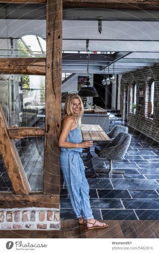 Woman standing in her comfortable country house, smiling timber timbers smile country houses cottage cottages Country Cottage leaning woman females women