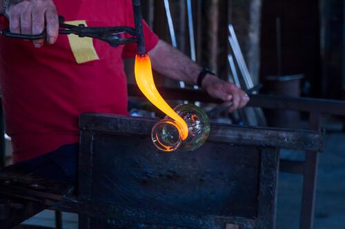 Man working with molten glass in a glass factory glass-blower shaping Forming At Work Job Occupation glassware glassblowing occupation profession