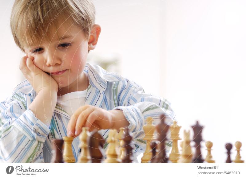 Portrait of thinking little boy playing chess helpless Helplessness Doubt Disbelief doubting skill Ability skilled serious earnest Seriousness austere