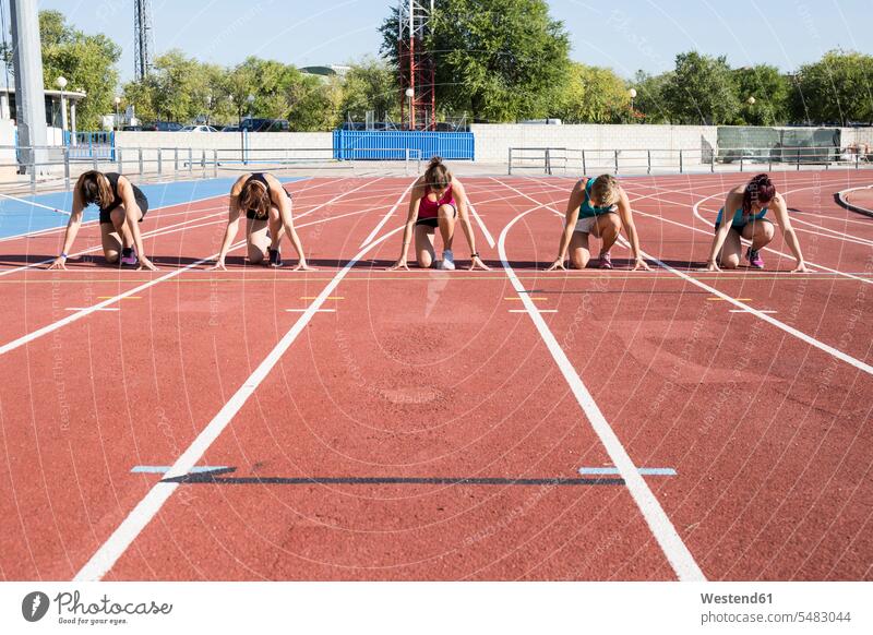 Female runners on tartan track in starting position sprinting athletics track and field athletics athletic sports athlete sportswoman athletes female athlete