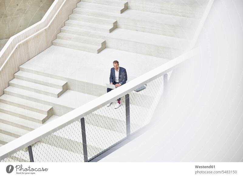 Businesssman sitting on stairs using laptop Laptop Computers laptops notebook stairway Businessman Business man Businessmen Business men computer computers