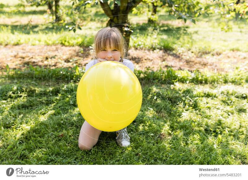 Girl inflating balloon on meadow girl females girls garden gardens domestic garden inflate blowing up blow up balloons meadows child children kid kids people