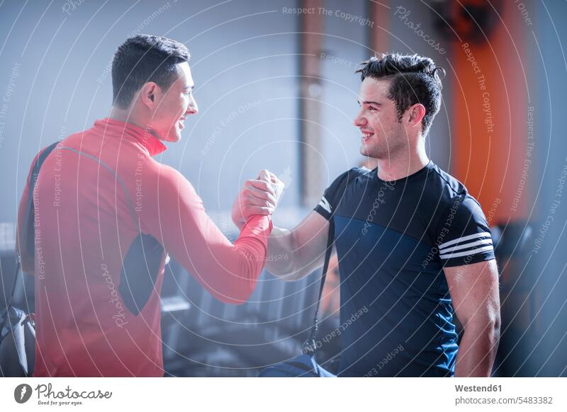 Two young men shaking hands in gym friends exercising exercise training practising smiling smile gyms Health Club friendship fitness sport sports Fitness