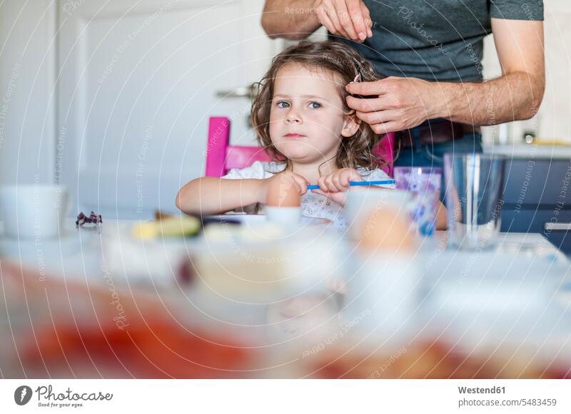 Father doing daughter's hair at breakfast table father pa fathers daddy dads papa daughters Breakfast parents family families people persons human being humans