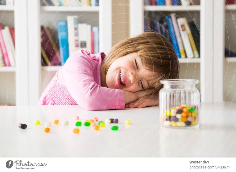 Portrait of happy little girl with glass of jelly beans pink Rosy bangs bangs hairstyle fringe hairstyles bangs hairstyles fringes bookshelf book shelf