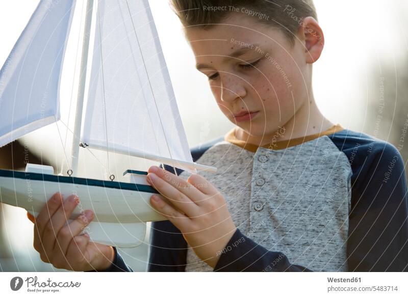 Boy with toy boat boy boys males Toy Boat child children kid kids people persons human being humans human beings playing serious earnest Seriousness austere