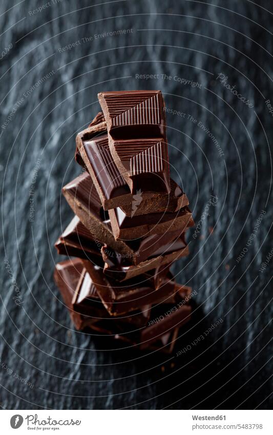 Pile of chocolate pieces on black slate black background black backgrounds large group of objects many objects nibbling snacking nibble stack stacked stacks