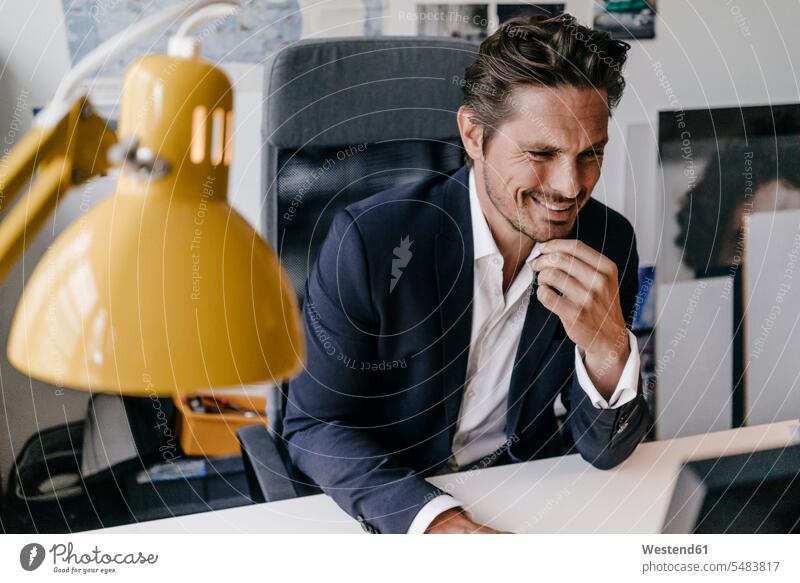 Smiling businessman working at desk desks Businessman Business man Businessmen Business men Office Offices smiling smile At Work Table Tables business people