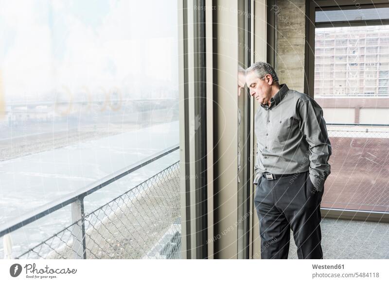 Exhausted senior businessman leaning against window Exhaustion Weary exhausted Businessman Business man Businessmen Business men windows serious earnest