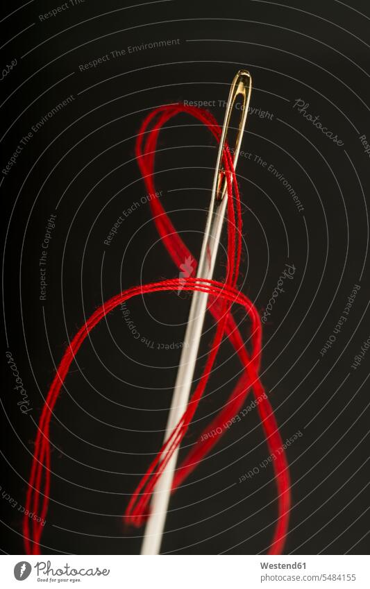 Red thread pulled through needle's eye needlework nobody black background black backgrounds hobby hobbies Handcraft handcrafted handmade threading needle eye