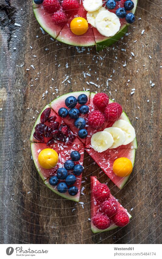Fruitcake made of watermelon garnished with various fruits sprinkled with coconut flakes red wooden piece pieces chunks part parts sliced ready to eat