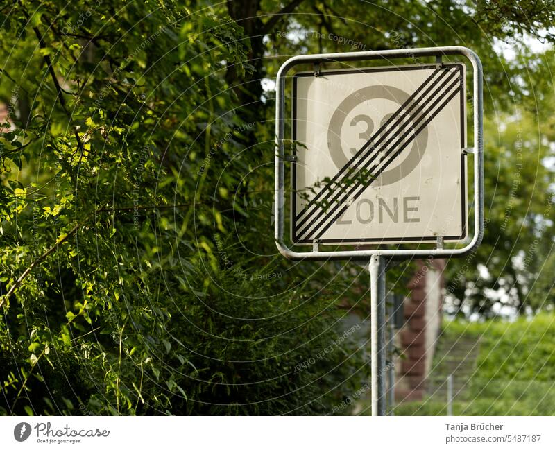 Zone 30 speed limit lifted, sign in greenery End zone 30 30 mph zone Limitation lifted Speed limit lifted Road sign Safety noise protection crossed out
