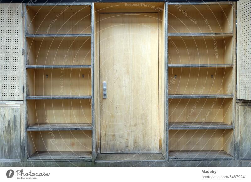 Wooden paneling with wooden door and empty shelves of a cashier's booth made of light natural wood at shaft XII of Zollverein colliery in Ruhr area in North Rhine-Westphalia in Germany