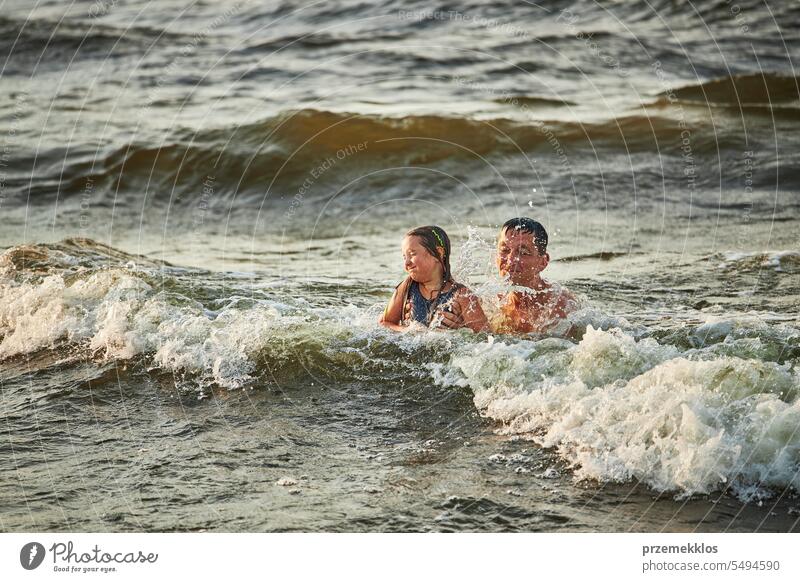 Little girl and her dad playing with waves in the sea. Family summer vacations. Kid playfully splashing with waves. Summer vacation on the beach ocean family