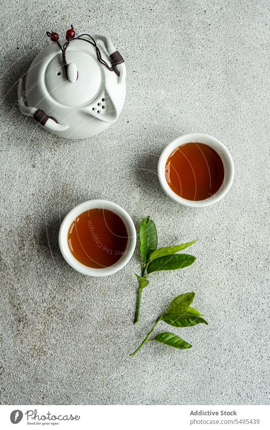 Tea set in Asian style with lemon leaves as decoration tea asian leaf table surface gray cup full drink beverage liquid jar ceramic green white brown isolated