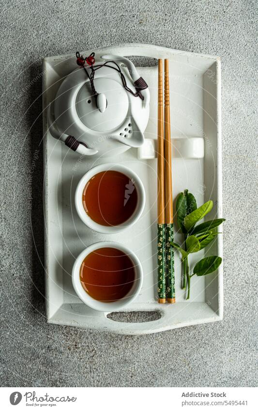 Tea set in Asian style with lemon leaves and chopsticks on tray as decoration tea asian leaf table surface gray cup full drink beverage liquid jar ceramic green