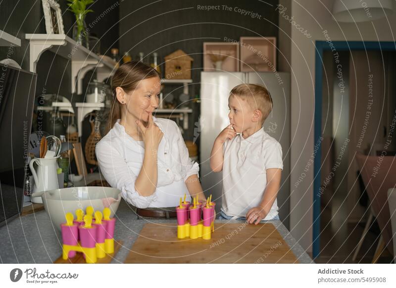 Woman and boy licking fingers and making popsicle in kitchen mother son looking ice cream molded woman cute family love dessert together tasty sweet food little