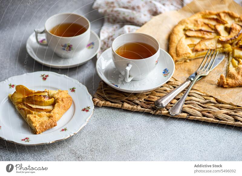 Apple galette and tea served on the concrete modern table apple pie piece cup teacup rustic tray gray food drink beverage liquid hot dessert yummy taste tasty